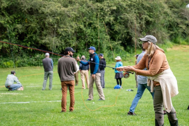 Instructor demonstrating cast to others on grass field.
